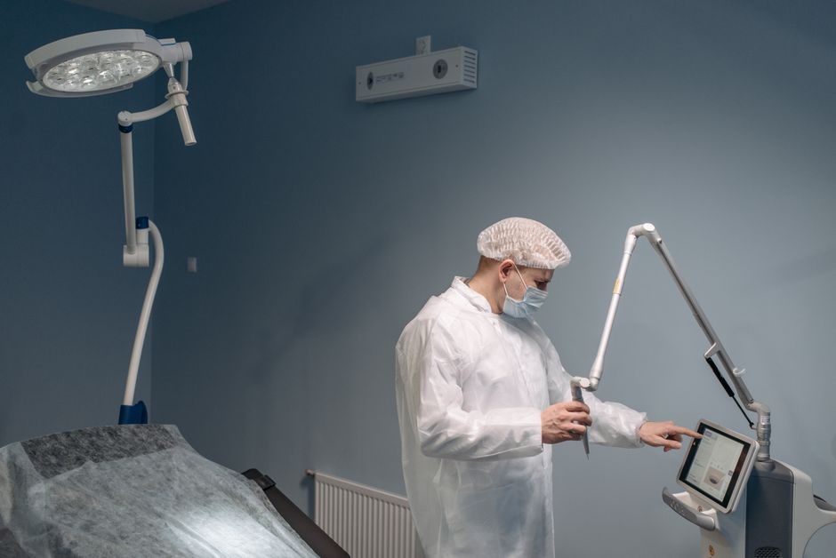 A professional doctor uses a laser machine in a modern operating room wearing protective gear.