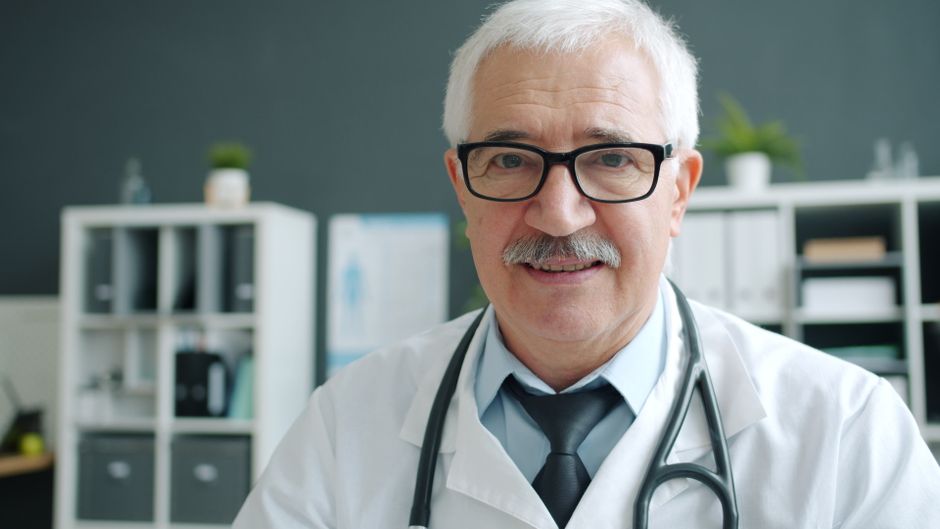 Senior doctor in his office wearing a stethoscope, ready to assist patients.