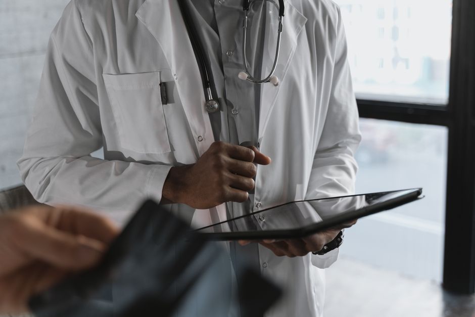 A professional medical practitioner holding a tablet, focused on work in a clinical setting.